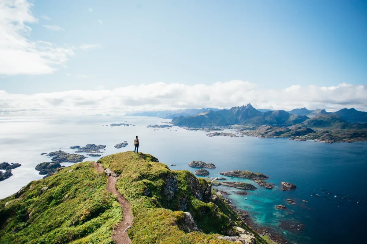A man standing on a mountain looking out at the ocean